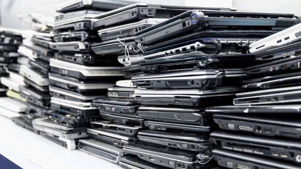 A pile of broken laptops stacked on a counter, illustrating the backlog and hidden costs of device downtime in schools.